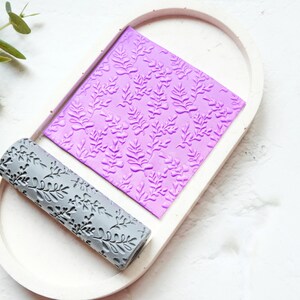 Może przedstawiać: Fioletowy wałek do ciasta z wzorem liści i szary wałek do ciasta z wzorem liści na białym tle.