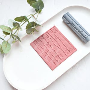 May include: Two silicone stamps for baking or crafting. One is a rectangular stamp with a birch tree pattern. The other is a cylindrical roller stamp with a birch tree pattern.