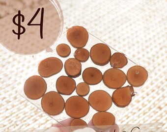 May include: Handmade resin and wood coaster with a circular design featuring multiple wood slices embedded in clear resin. The coaster is $4.