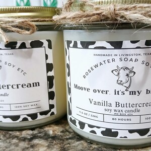 Może przedstawiać: Dwa szklane słoiki z białymi pokrywkami i czarno-białymi etykietami z nadrukiem krowy. Etykiety głosi: "Handmade in Livingston, Texas, Rosewater Soap Soy Etc, Moove over, it's my birthday! Vanilla Buttercream Soy Wax Candle, 11.5 oz / 326g, PO Box 424, 80 Hours, 100% Soy Wax".