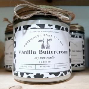 Może przedstawiać: Szklana świeca w słoiku z białą etykietą, na kt&oacute;rej widnieje napis "Vanilla Buttercream" i "soy wax candle". Etykieta zawiera r&oacute;wnież ilustrację krowy i tekst "Handmade in Livingston, Texas, Rosewater Soap Soy Etc, PO Box 424, 80 Hours, 11.5 oz/326g, 100% Soy Wax".