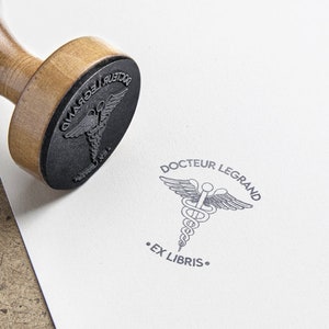 Tampon Caducée médecine personnalisé. Tampon à encre Ex Libris Médecine. Grand tampon personnalisable Caducée. Tampon Ex Libris