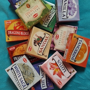 May include: Assortment of HEM incense cones in various scents, including Dragon's Blood, Sandalwood, White Sage, and Tangerine. The cones are packaged in colorful boxes with the HEM logo and scent name.