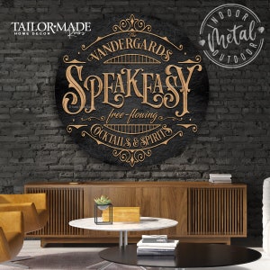 May include: A black metal sign with gold lettering that reads "The Vandergards Speakeasy free-flowing cocktails & spirits". The sign is hanging on a brick wall.