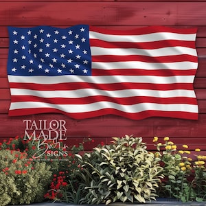 May include: A red wooden background with an American flag hanging on it. The flag is waving in the wind. There are green plants and red flowers in the foreground. The text "Tailor Made Barn Signs" is visible in the lower left corner of the image.