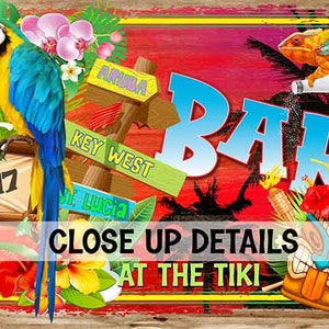 May include: A colourful tiki bar sign with the word "BAR" in large blue letters. The sign features a parrot, a chameleon, tropical flowers, and palm trees. It also includes signs for Aruba, Key West, and St. Lucia. The sign says "Since 2017" at the bottom.