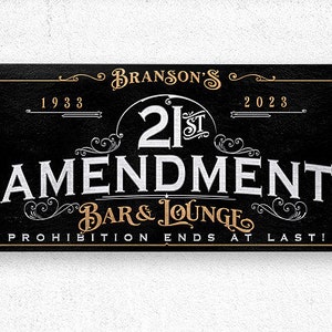 May include: A black and gold sign with the text "Branson's 21st Amendment Bar & Lounge Prohibition Ends At Last!" with the years 1933 and 2023.
