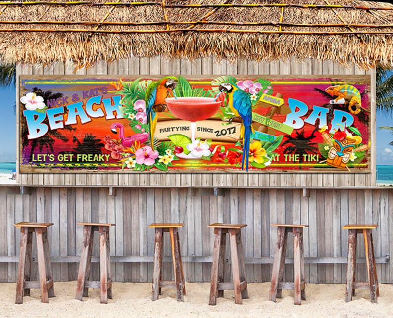 May include: A colourful beach bar sign with the text "Nick & Kat's Beach Bar" and the tagline "Let's Get Freaky". The sign also includes a tropical sunset, parrots, a flamingo, and the text "Partying Since 2017".