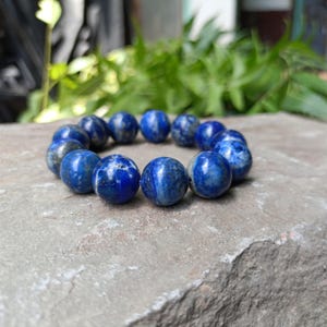 Stack of 6mm, 8mm, 10mm, and 12mm Lapis bracelets in hand