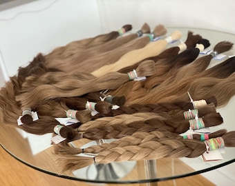 以下が含まれることがあります： さまざまな茶色のヒューマンヘアエクステンションのコレクション。ストレートのものと編まれたものがあります。