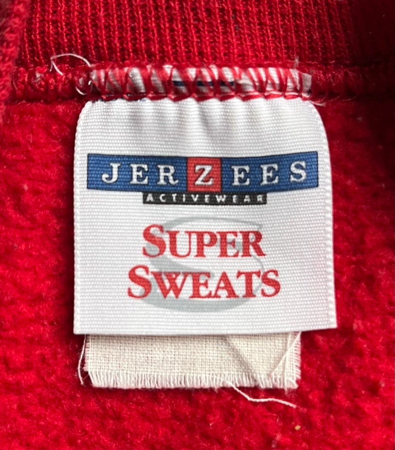 May include: A white tag with the text "JERZEES ACTIVEWEAR SUPER SWEATS" in blue and red lettering.