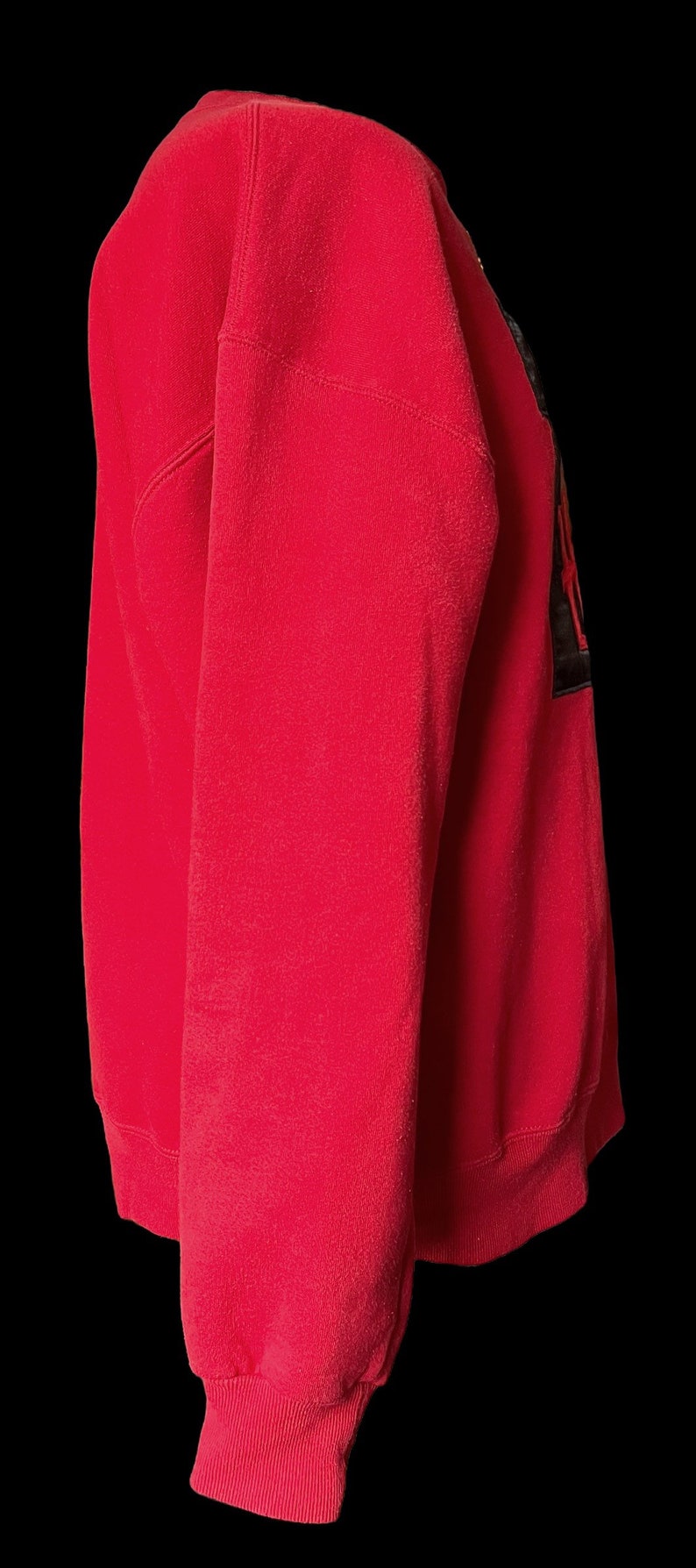 May include: A red sweatshirt with a black and white graphic on the front. The sweatshirt has a ribbed collar and cuffs.