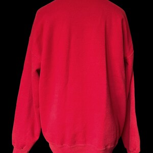 May include: A red sweatshirt with long sleeves and a crew neck.