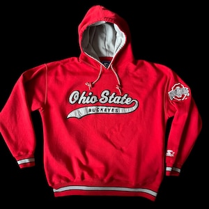 May include: A red Ohio State Buckeyes hooded sweatshirt with white and black accents. The sweatshirt features the words "Ohio State Buckeyes" in a script font across the chest. The hood is lined with gray fabric.