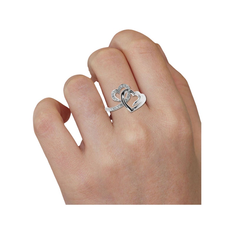 May include: A silver ring with two intertwined heart designs. The hearts are set with small clear stones.
