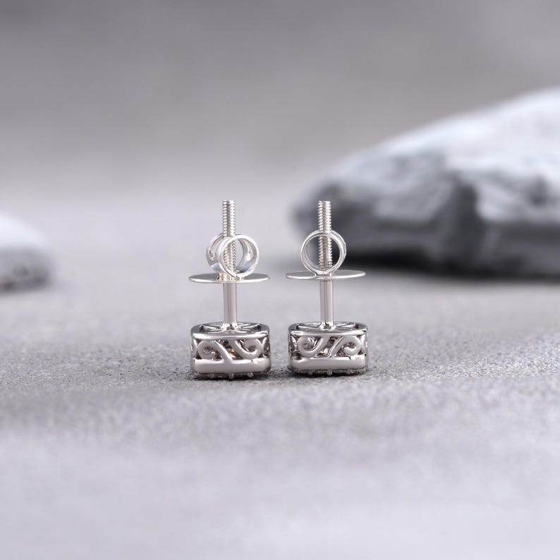 May include: A pair of silver stud earrings with a square-shaped design featuring a small cluster of clear stones.
