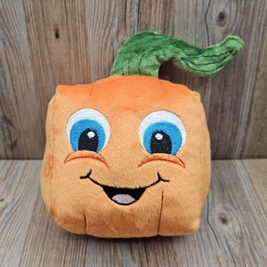 May include: A plush orange carrot toy with a smiling face, blue eyes, and a green stem. The carrot has a friendly expression, making it a fun and whimsical item for children or as a decorative piece.