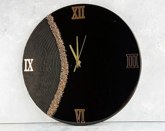 May include: Black and gold clock with Roman numeral markings. The clock face is divided in half, with one side featuring a textured black surface and the other side featuring a black surface with gold glitter.
