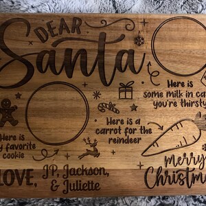 May include: Wooden serving board with engraved text and illustrations for Santa. The board includes the words "Dear Santa" and "Merry Christmas", along with spaces for cookies, milk, and carrots. It is signed "Love, JP, Jackson, & Juliette."