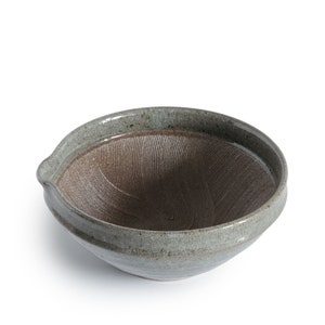 May include: A gray ceramic suribachi, a traditional Japanese mortar and pestle used for grinding ingredients like sesame seeds, spices, and wasabi.