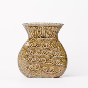 May include: A brown ceramic vase with a rounded body and a wide mouth. The vase has a textured surface with a white glaze and a decorative pattern of loops and lines.