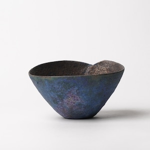 May include: A small, hand-formed bowl with an irregular, organic rim. The exterior features a textured, mottled finish in deep shades of blue, purple, and dark charcoal, while the interior displays a darker, metallic-toned surface with a rough, uneven appearance.