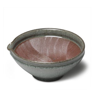May include: A gray ceramic suribachi, a Japanese mortar and pestle, with a red interior and a textured surface.
