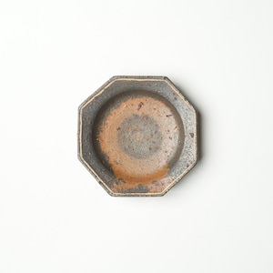 May include: A dark gray octagonal ceramic dish with a light brown interior. The dish has a slightly textured surface and a subtle sheen.