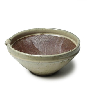 May include: A ceramic mortar bowl with a light beige exterior and a textured, reddish-brown interior. The bowl has a spout and a wide rim. The interior features a ridged surface for grinding ingredients. The bowl is designed for food preparation.