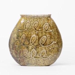 May include: A green ceramic vase with a rounded shape and a textured surface. The vase has a design of three rows of stylized "eee" letters.