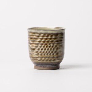 May include: A cylindrical ceramic cup featuring a repeating textured pattern of small, vertical brown and tan dashes across the exterior. The rim is finished with a smooth, light-colored glaze, while the base remains a solid, unglazed brown clay.