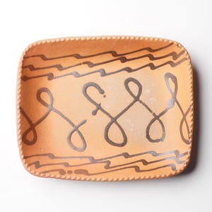 May include: A rectangular terracotta serving dish with a decorative design of brown wavy lines and swirls.