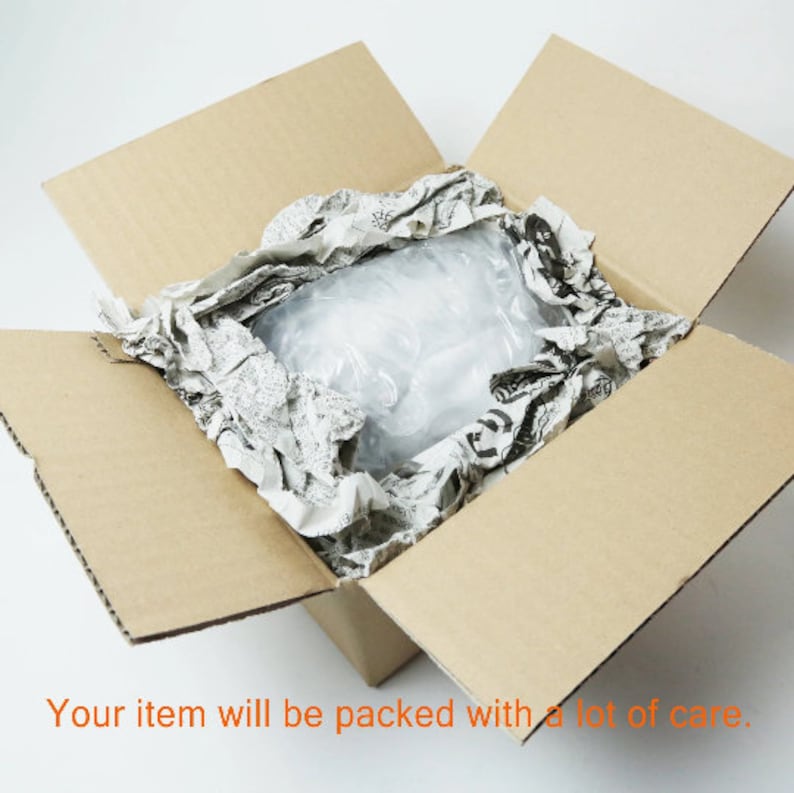 May include: A brown cardboard box with the top open, revealing a white and gray crumpled paper packing material inside. The text "Your item will be packed with a lot of care." is printed below the box.