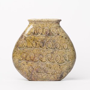 May include: A ceramic vase with a rounded, teardrop shape. The vase is decorated with a repeating pattern of loops and swirls, and has a light brown glaze with hints of green and yellow.