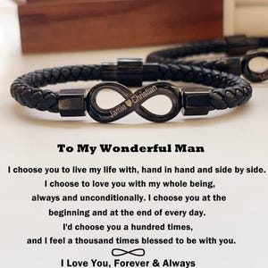 May include: A black leather bracelet with an infinity symbol charm engraved with the names "Jamie" and "Christian" and a heart symbol. The bracelet is accompanied by a message that reads "To My Wonderful Man I choose you to live my life with, hand in hand and side by side. I choose to love you with my whole being, always and unconditionally. I choose you at the beginning and at the end of every day. I'd choose you a hundred times, and I feel a thousand times blessed to be with you. I Love You, Forever & Always"