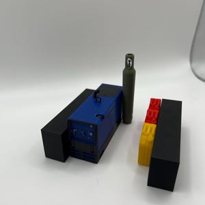 Peut inclure: Une machine &agrave; souder bleue et noire avec une bouteille de gaz verte et des blocs rouges et jaunes.