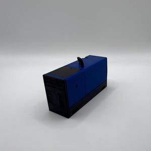 Peut inclure: Mod&egrave;le r&eacute;duit d'un g&eacute;n&eacute;rateur, de couleur bleue et noire. Le g&eacute;n&eacute;rateur a un dessus noir et un corps bleu avec une poign&eacute;e noire.