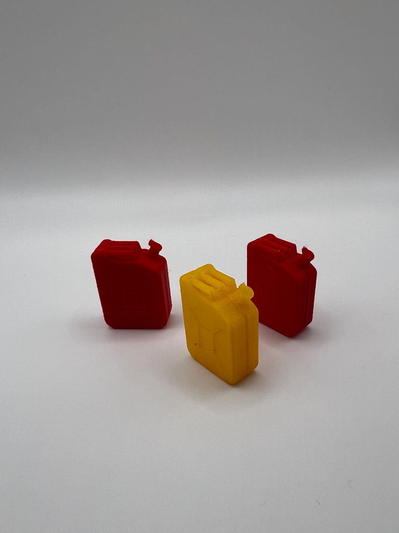 Peut inclure: Trois petits bidons d'essence en plastique, deux rouges et un jaune.