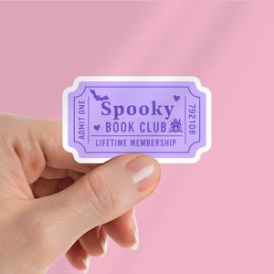 May include: A purple and white sticker in the shape of a ticket. The sticker reads "Spooky Book Club" with a bat and heart graphic. The words "Lifetime Membership" are also printed on the sticker.