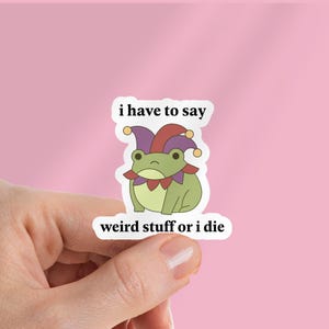 Puede incluir: Una pegatina troquelada que muestra una rana de color verde claro con un gorro de bufón morado y rojo con cascabeles amarillos. El texto sobre la rana dice i have to say y debajo dice weird stuff or i die en una fuente negra.