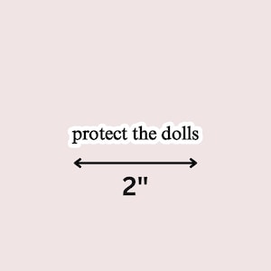 May include: A sticker with the text "protect the dolls" in a black, bold font. The sticker is 2 inches (5 cm) wide, indicated by a black arrow and the number 2. The background is a light pink color.