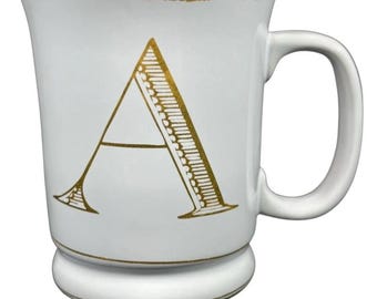Caneca com alça e monograma da letra "A" em dourado, inicial C, da Williams Sonoma.