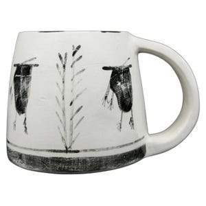May include: A white ceramic mug with a tapered shape and a thick handle. The exterior features hand-painted black illustrations of two stylised figures and a central plant-like stalk, with a solid black band encircling the base of the mug.