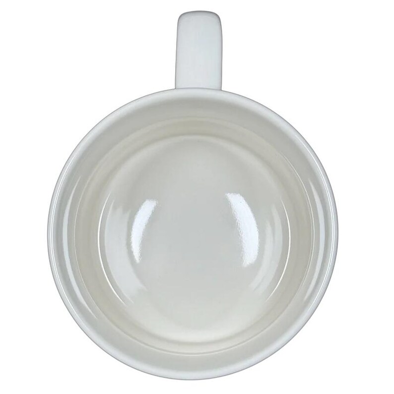 Top view of white ceramic Alexandre Dumas G monogram initial mug empty with handle on black background