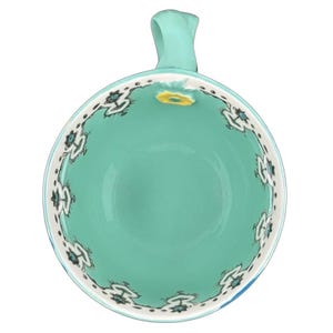 Top view Anthropologie Elka Ayaka green floral pedestal mug turquoise interior with white floral border and handle
