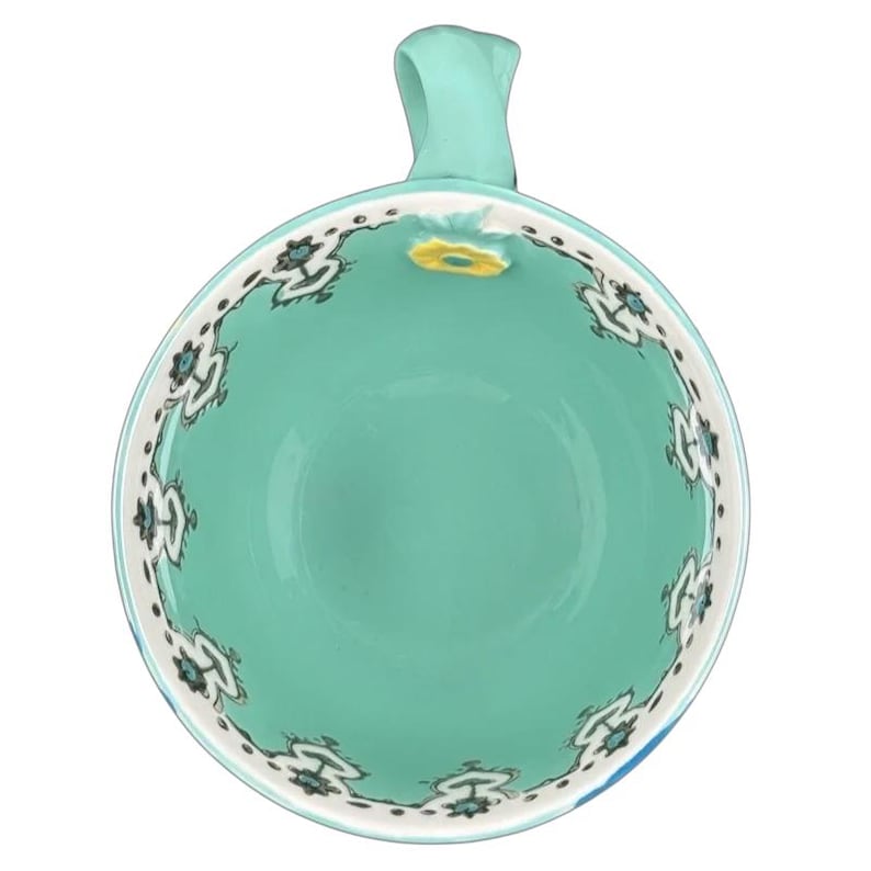 Top view Anthropologie Elka Ayaka green floral pedestal mug turquoise interior with white floral border and handle