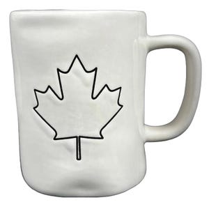 Puede incluir: Taza de cerámica blanca con un contorno negro de una hoja de arce. La taza tiene un asa curvada y una superficie ligeramente texturizada. Diseño sencillo y elegante, ideal para café o té.