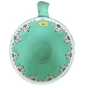 Top view Anthropologie Elka Ayaka green floral pedestal mug showing turquoise interior white floral border and yellow bloom