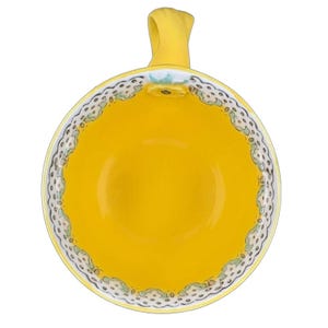 Top view of Anthropologie Elka Ayaka floral pedestal mug bright yellow interior with scalloped floral rim and handle