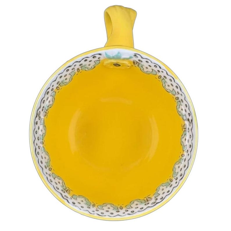 Top view of Anthropologie Elka Ayaka floral pedestal mug bright yellow interior with scalloped floral rim and handle